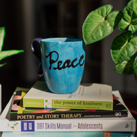 Gallery Photo of Here is a glimpse of my soothing tea mug and some essential books I use: poetry therapy and DBT!