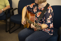 Gallery Photo of A music therapist plays guitar in many sessions with older adults. Piano, too!