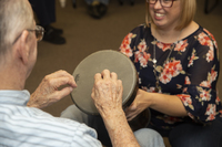 Gallery Photo of Here, Rachelle holds a djembe for a client to play in a group session.