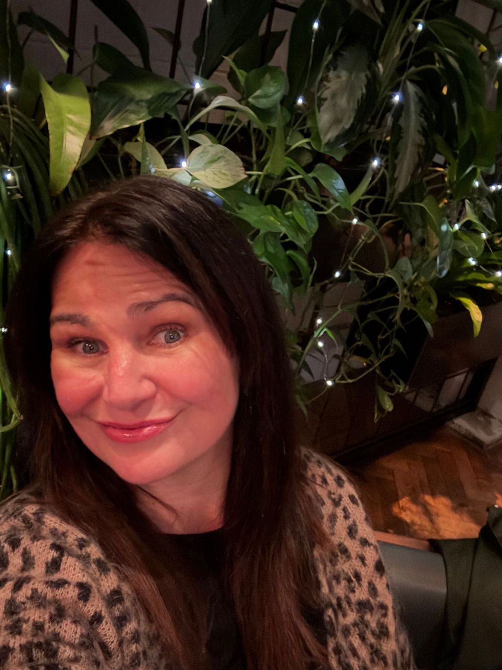 A moment of quiet contentment, framed by greenery and gentle fairy lights.  